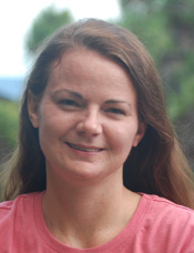 A woman with long hair wearing a pink shirt.